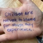 Writing on a hand 'Children are never to blame for abuse they experience".